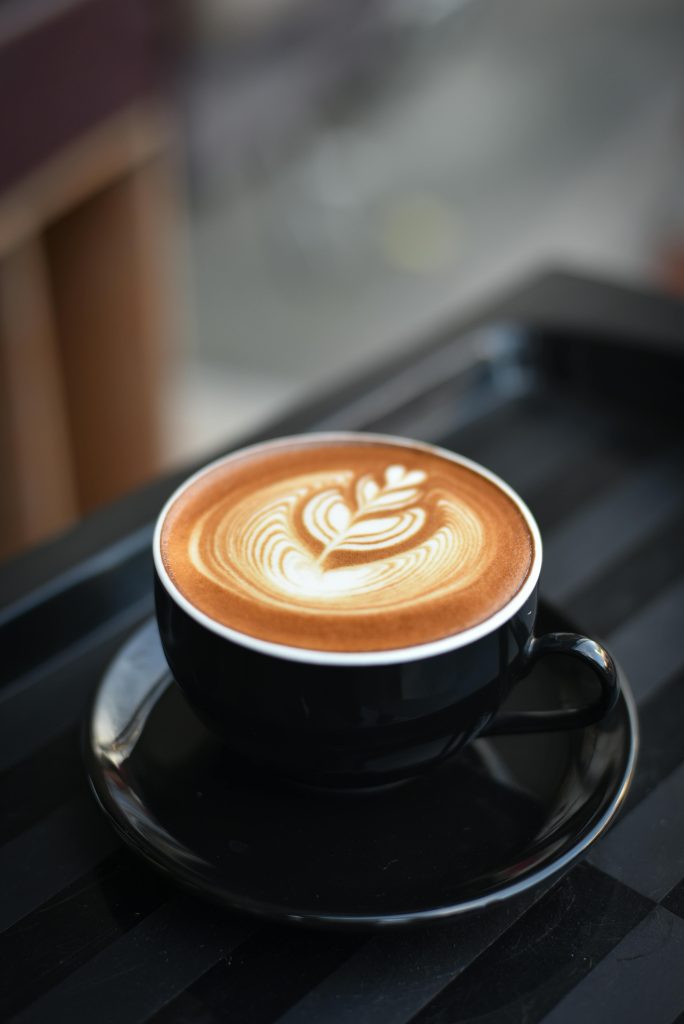 pexels-photo-312418-312418 A beautifully crafted cappuccino with intricate latte art in a black ceramic mug on a dark surface.